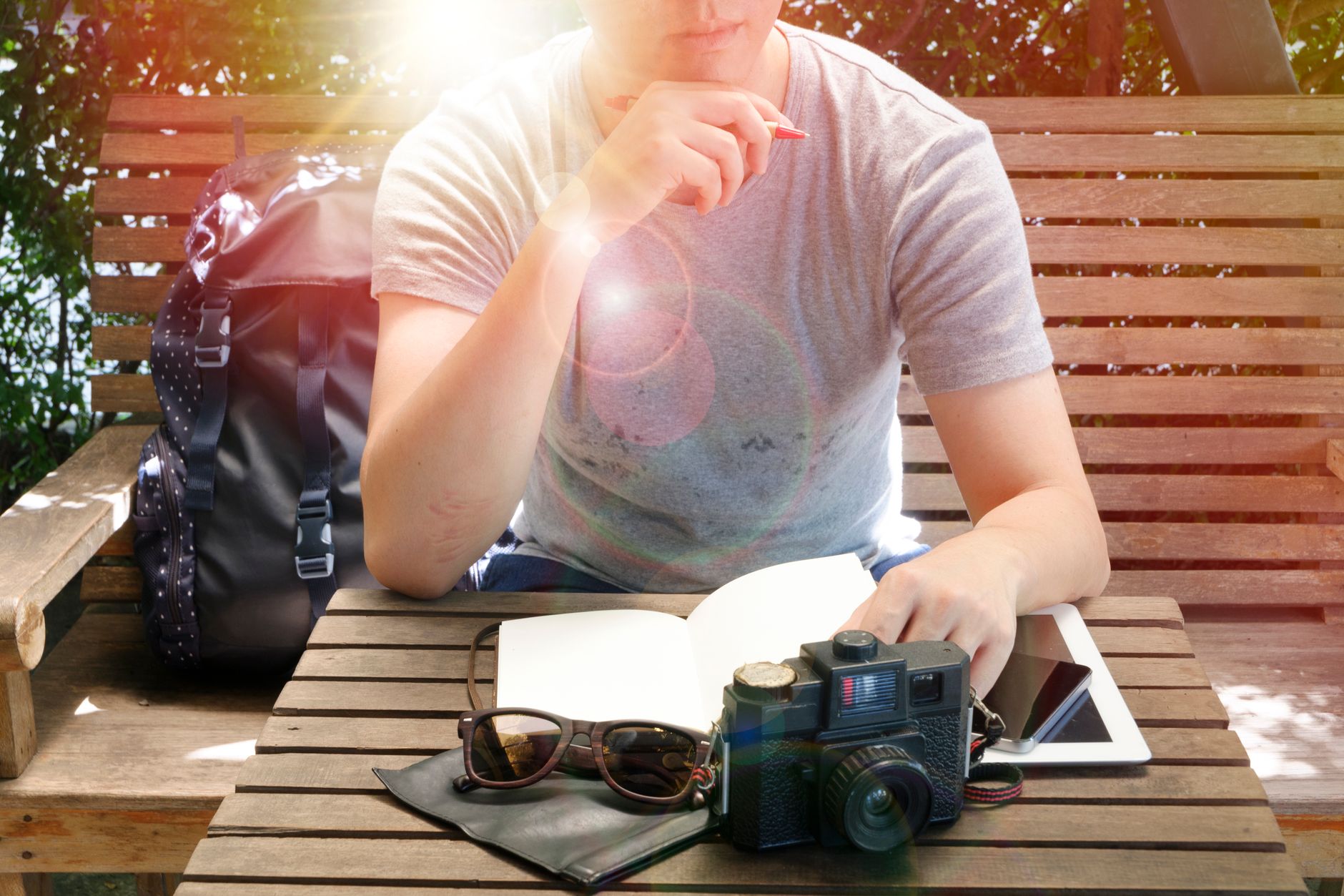 Travel journal notebook and camera resting on a rustic wooden table